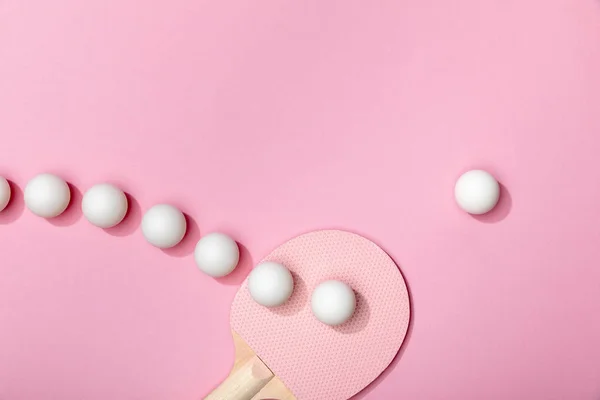 Flat lay com bolas de tênis de mesa de plástico branco e raquete no fundo rosa — Fotografia de Stock