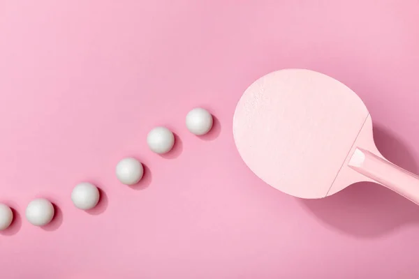 Vista superior de pelotas de tenis de mesa blancas y raqueta sobre fondo rosa - foto de stock