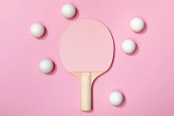 Vista superior de pelotas de tenis de mesa blancas cerca de raqueta rosa de madera sobre fondo rosa - foto de stock