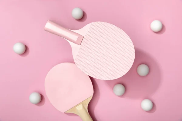 Vista superior de pelotas blancas de tenis de mesa y raquetas sobre fondo rosa - foto de stock