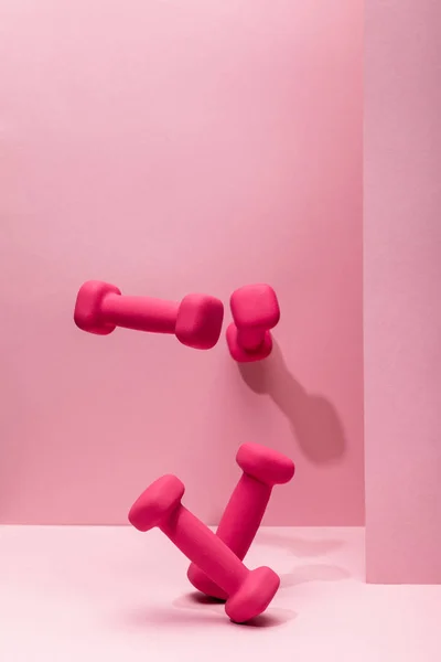 Pink bright dumbbells flying in air on pink background — Stock Photo
