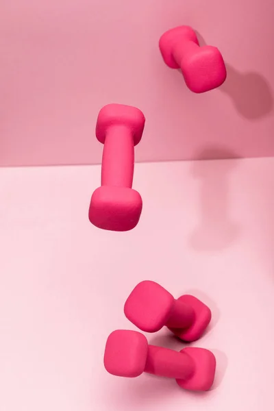 Pink bright dumbbells flying in air on pink background — Stock Photo