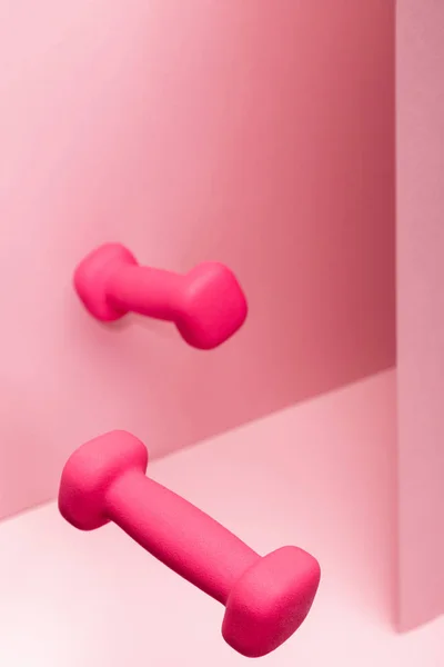 Pink bright dumbbells flying in air on pink background — Stock Photo