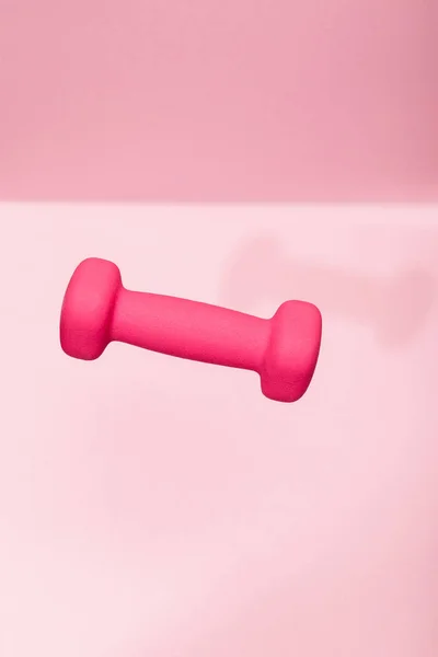 Pink bright dumbbell levitating in air on pink background — Stock Photo