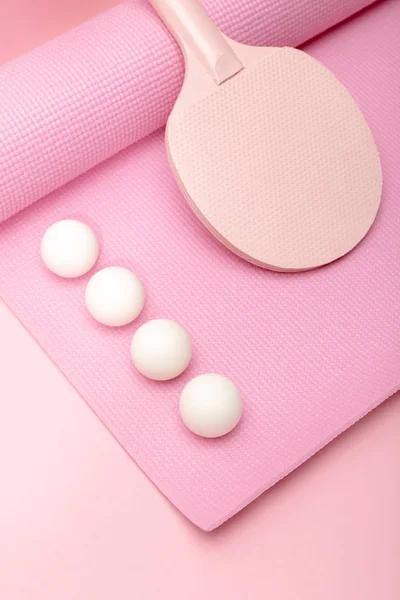 Pelotas blancas de ping-pong y raqueta en la colchoneta de fitness sobre fondo rosa - foto de stock