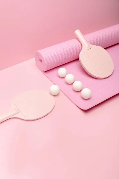 Pelotas blancas de ping-pong y raquetas en la colchoneta de fitness sobre fondo rosa - foto de stock