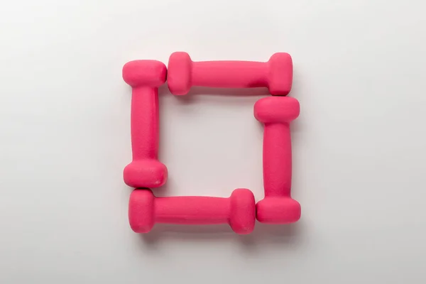 Top view of frame with pink dumbbells on white background — Stock Photo