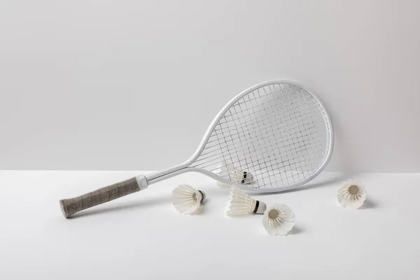 Lanzaderas de bádminton blanco cerca de raqueta blanca sobre fondo blanco - foto de stock