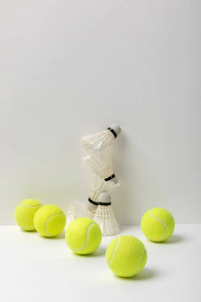 Navette badminton bianche e palline da tennis gialle su sfondo bianco — Foto stock