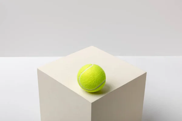 Bright yellow tennis ball on cube on white background — Stock Photo