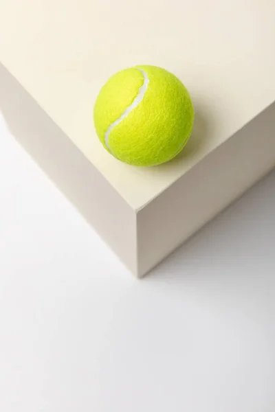 Bright yellow tennis ball on cube on white background — Stock Photo