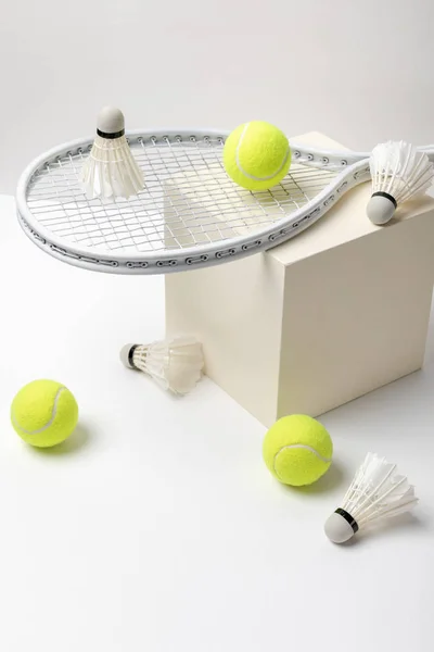 Raquette de tennis et balles de tennis jaune vif avec des navettes sur cube sur fond blanc — Photo de stock