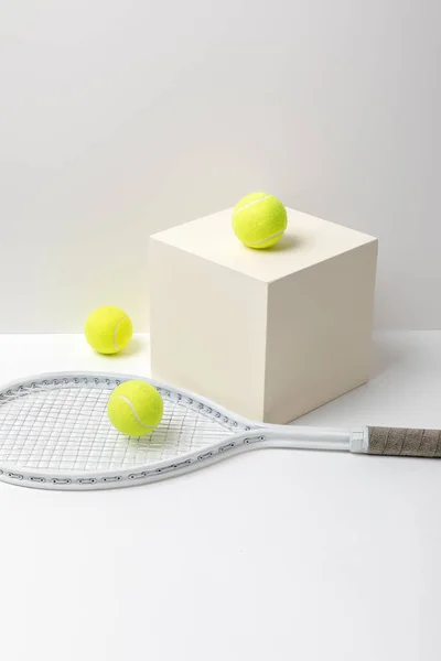 Raquete de tênis e bolas de tênis amarelo brilhante no cubo no fundo branco — Fotografia de Stock