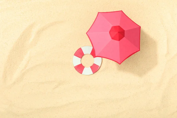 Top view of paper beach with lifebuoy and pink umbrella on textured sand — Stock Photo