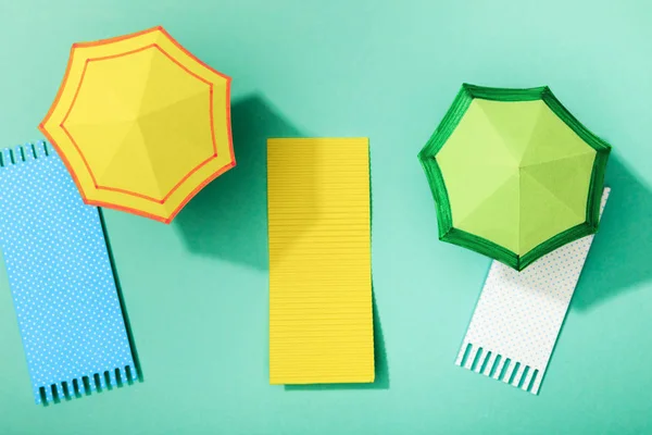 Top view of paper towels and umbrellas on turquoise background — Stock Photo