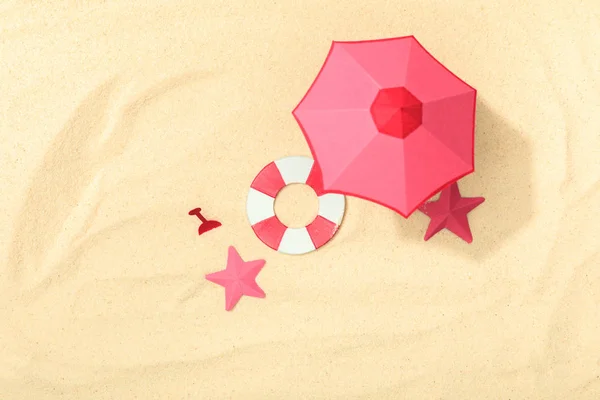 Top view of paper beach with lifebuoy, pink umbrella and starfishes on textured sand — Stock Photo