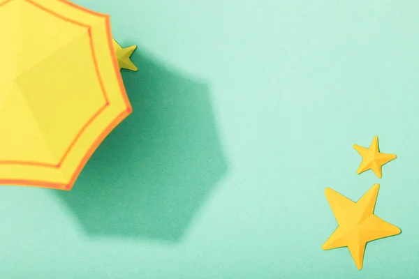 Верхний вид бумаги желтый зонтик возле морских звезд на бирюзовом фоне — стоковое фото