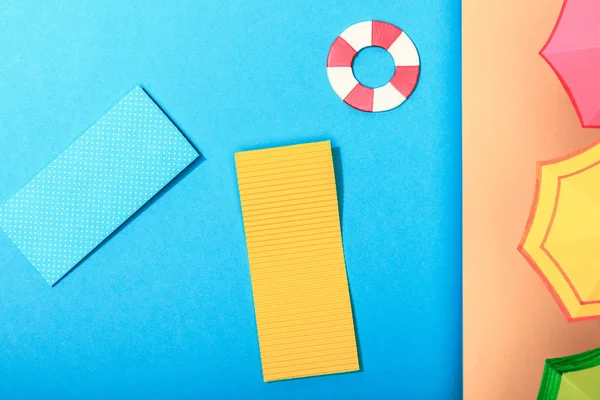 Top view of paper calm blue sea with pool floats and lifebuoy and umbrellas on shore — Stock Photo