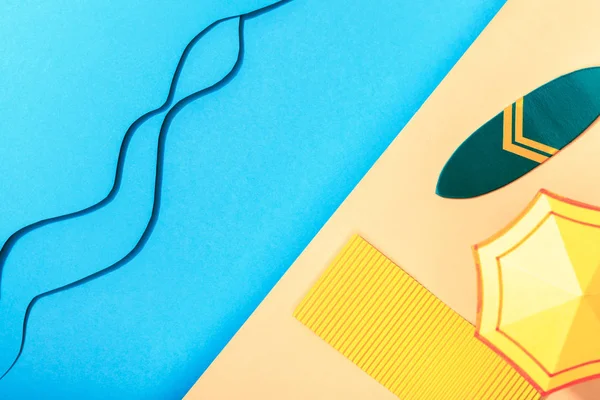 Top view of paper blue sea with waves near shore with surfboard, towel and umbrella — Stock Photo