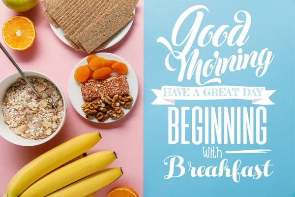 Vista superior de frutas frescas, pan crujiente y cereales de desayuno sobre fondo azul y rosa con buenos días, tener un gran día a partir de letras de desayuno - foto de stock