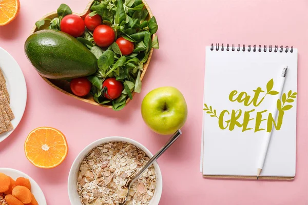 Vista dall'alto di alimenti dietetici freschi e notebook con scritte verdi su sfondo rosa — Foto stock