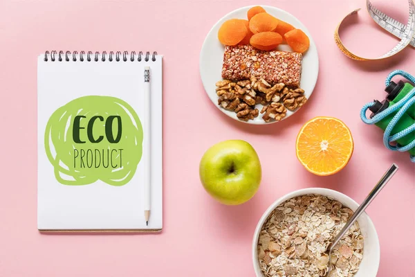 Draufsicht auf frische Diät-Lebensmittel, Maßband, Springseil und Notizbuch mit Ökoprodukt-Schriftzug auf rosa Hintergrund — Stockfoto