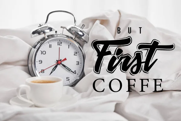 Café na xícara branca no pires perto de relógio de alarme de prata em cobertor branco com mas primeira ilustração café — Fotografia de Stock