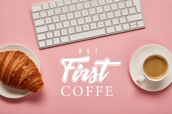 Top view of computer keyboard near coffee and croissant on pink background with but first coffee lettering — Stock Photo