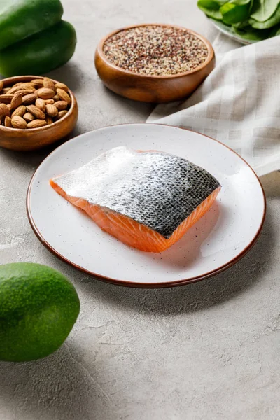 Fresh raw salmon on white plate near nuts and avocado, ketogenic diet menu — Stock Photo