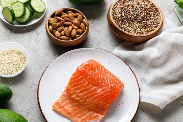 Frischer roher Lachs auf weißem Teller in der Nähe von Nüssen und Gemüse, ketogene Speisekarte — Stockfoto