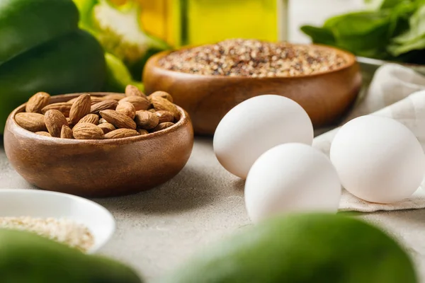 Foco seletivo de nozes em tigelas entre legumes e ovos verdes, menu de dieta cetogênica — Fotografia de Stock