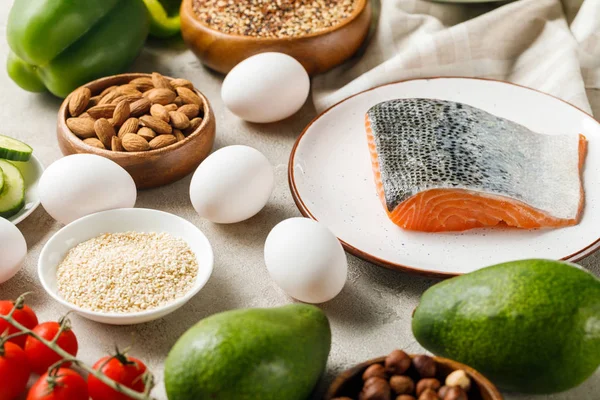 Saumon cru sur assiette blanche près de noix, légumes et œufs, menu diététique cétogène — Photo de stock