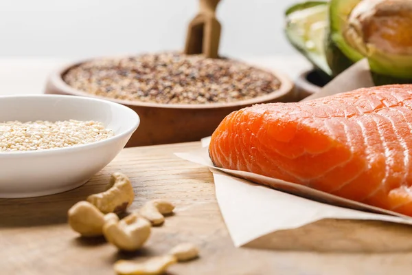 Focus sélectif saumon cru frais près des noix sur planche à découper en bois, menu diététique cétogène — Photo de stock