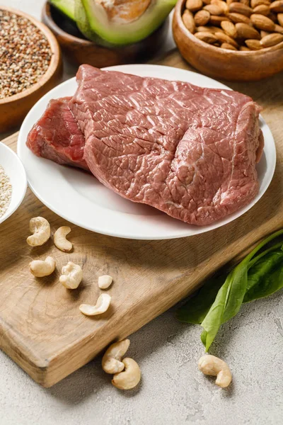 Carne cruda su tagliere di legno con noci, menù dietetico chetogeno — Foto stock