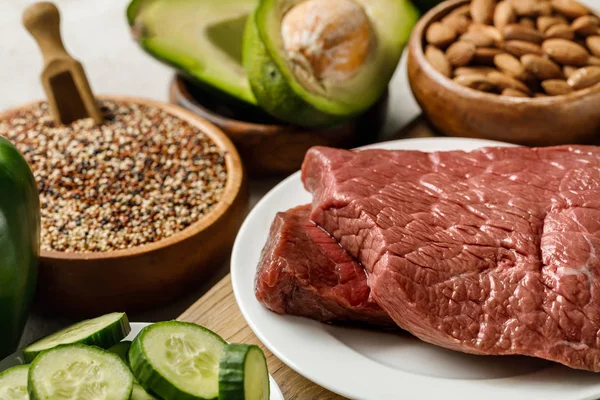 Orientation sélective de la viande crue près de noix, gruaux et légumes verts, menu diététique cétogène — Stock Photo