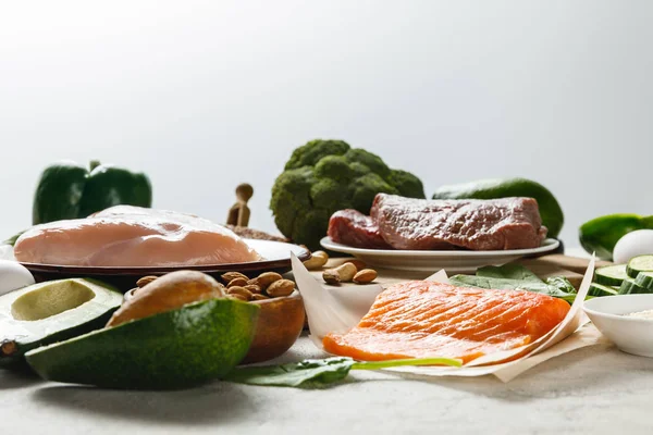 Frischer roher Lachs, Fleisch und Hühnerbrust in der Nähe von grünem Gemüse isoliert auf grauer, ketogener Speisekarte — Stockfoto