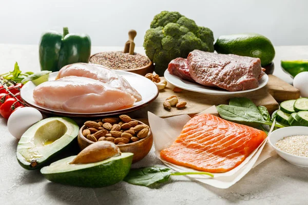 Poitrines crues de saumon, de viande et de poulet à proximité de légumes verts isolés au menu diététique gris et cétogène — Stock Photo