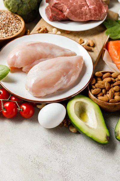 Carne crua fresca e peitos de frango perto de legumes e nozes, menu de dieta cetogênica — Fotografia de Stock