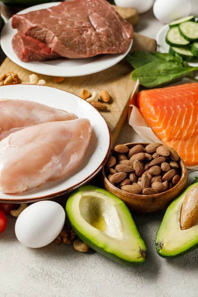 Свежий лосось, куриные грудки и мясо рядом с орехами и авокадо, кетогенное меню — стоковое фото
