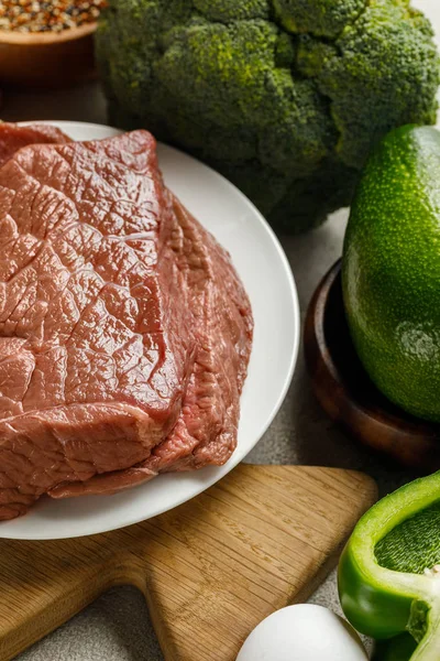 Close up view of raw meat near egg and avocado, , ketogenic diet menu — Stock Photo