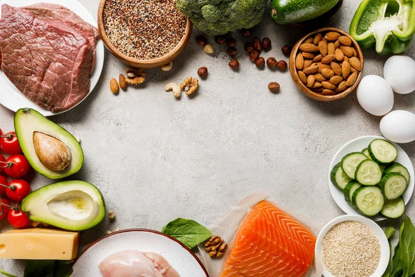 Ansicht von rohem Lachs, Hühnerbrust und Fleisch in der Nähe von Nüssen, Milchprodukten und Gemüse auf grauem Hintergrund mit Kopierfläche, ketogene Speisekarte — Stockfoto