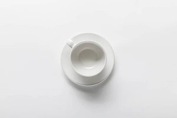 Vista superior da xícara branca vazia no pires no fundo branco — Fotografia de Stock