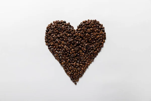 Вид зверху на серце зі свіжих кавових зерен на білому фоні — стокове фото