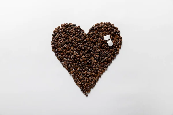 Вид зверху на серце з кавових зерен з цукром на білому тлі — стокове фото