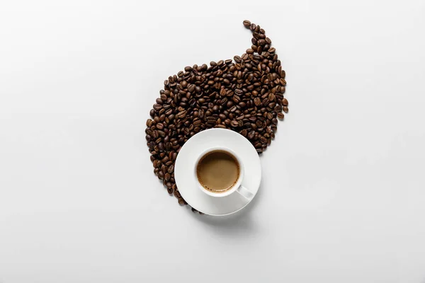 Vista superior del café en taza cerca de la hoja hecha de granos de café sobre fondo blanco - foto de stock