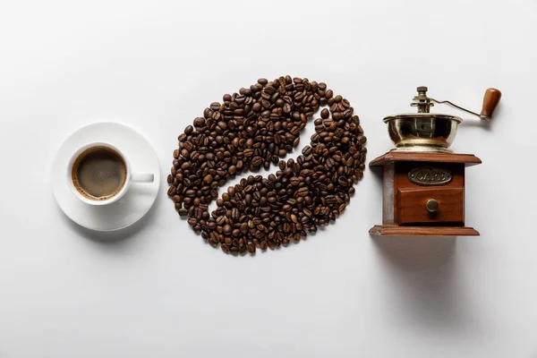 Vista superior de grãos de café, xícara de café e retro moedor de café no fundo branco — Fotografia de Stock