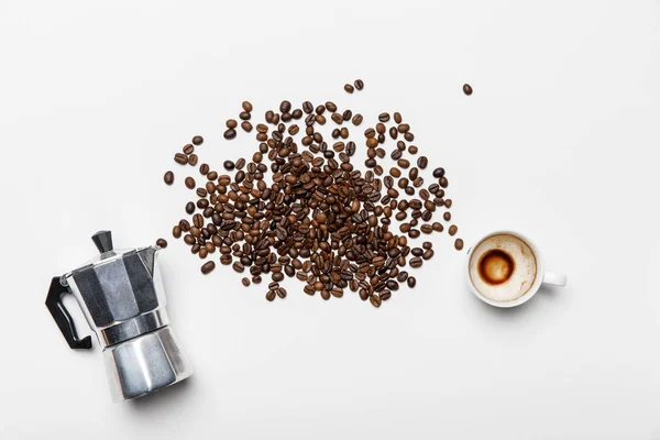 Vista dall'alto della caffettiera in alluminio, chicchi di caffè sparsi e tazza su sfondo bianco — Foto stock