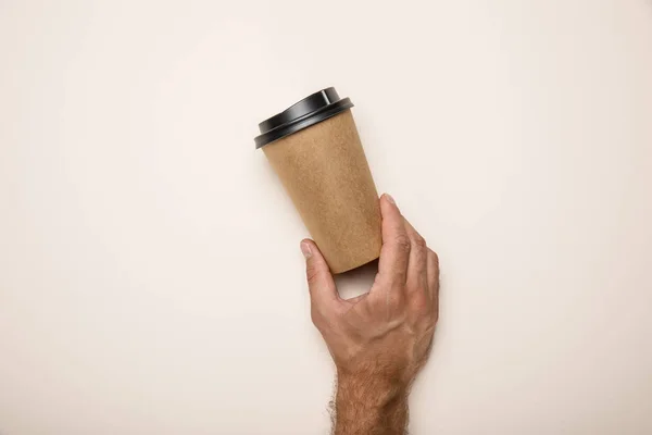 Corte vista de homem segurando copo de papel no fundo bege — Fotografia de Stock