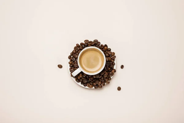Tasse von oben mit leckerem Kaffee auf Kaffeekörnern auf beigem Hintergrund — Stockfoto