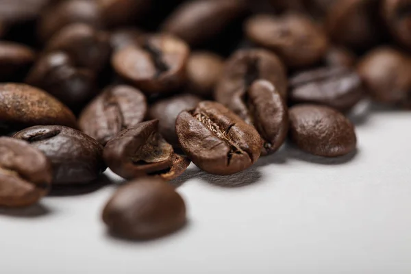 Vista da vicino di deliziosi chicchi di caffè freschi testurizzati sulla superficie bianca — Foto stock